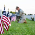 Flag and mixed flowers at headstone
